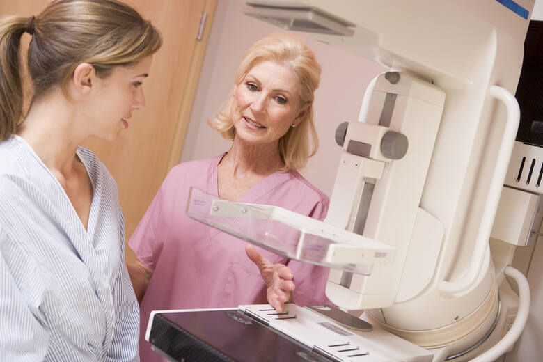Kobieta w średnim wieku rozmawia z lekarką przy mammografie