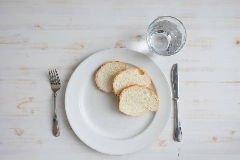 Kromki chleba na talerzu i szklanka wody