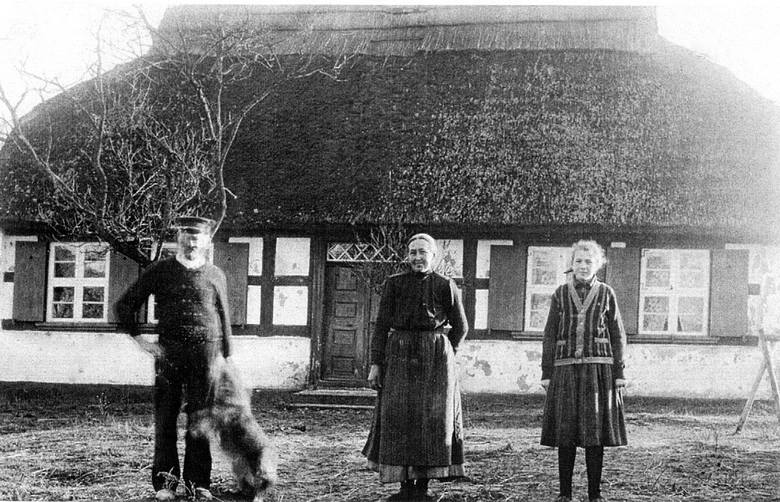 Na fotografii rodzina z psem przed, charakterystyczną dla tamtego okresu, chatą z dachem ze strzechy w Przytorze. Zdjęcie pochodzi z XIX wieku. 