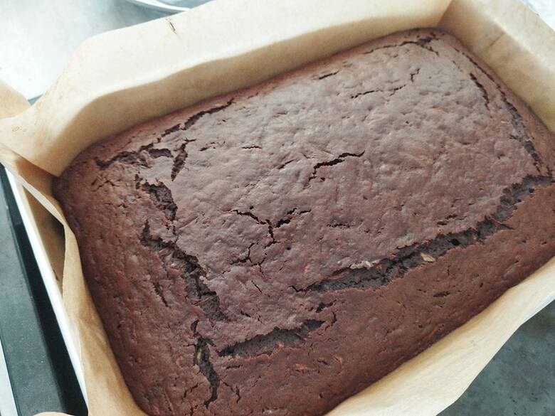 Gdy ciasto wystygnie przygotuj polewę: podgrzej śmietankę i dodaj do niej kostki czekolady, wymieszaj na gładką polewę.