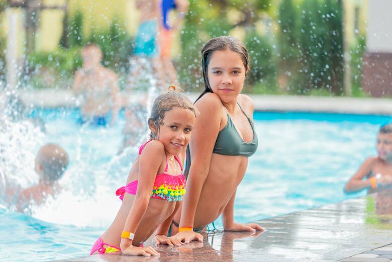 Dwie nastolatki w kostiumach kąpielowych pozują w basenie