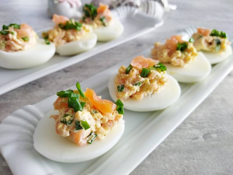 Nakładaj farsz na jajka i udekoruj odłożonym wcześniej szczypiorkiem i kawałeczkiem łososia.