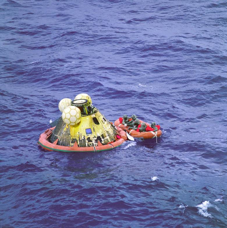 Załoga Apollo 11 czeka na transport helikopterem. Czwartym mężczyzną na tratwie ratunkowej jest pływak podwodnego zespołu  United States Navy. Wszyscy