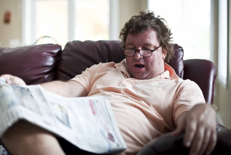 Mężczyzna z otyłością śpi na siedząco i chrapie