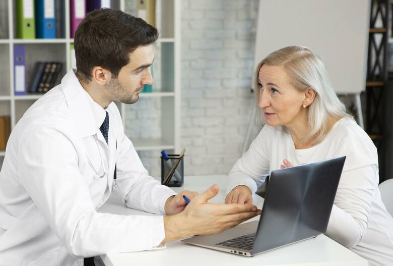 Pacjentka rozmawia z lekarzem przy biurku przed komputerem