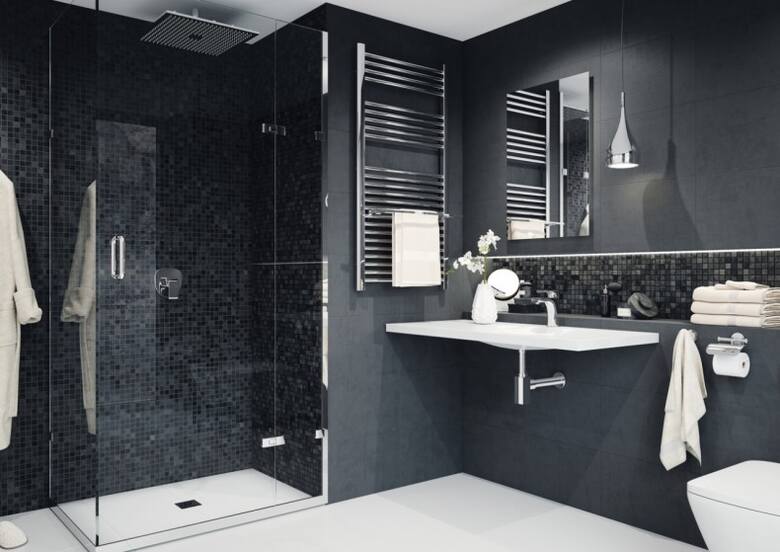 Ciemna łazienka z przeszklonym prysznicem i piękną mozaiką to niezwykle eleganckie połączenie.