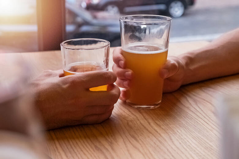 Dwie szklanki piwa na stole w dłoniach