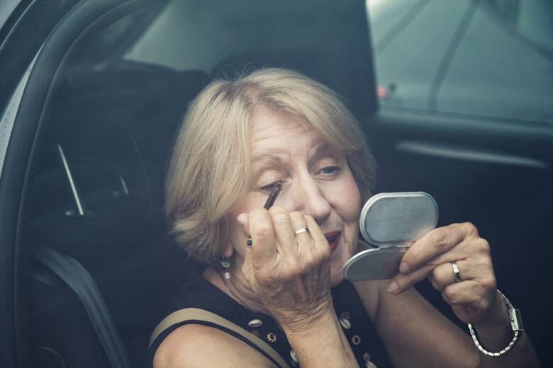Dojrzała kobieta robi makijaż w samochodzie