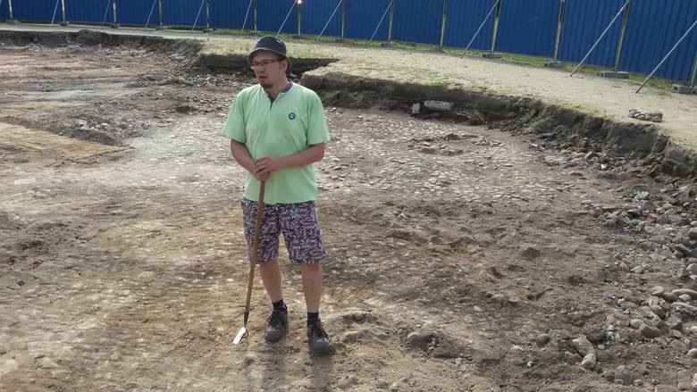 Archeolog Oktawian Wróblewski odsłania stary bruk, znaleziony pod niecką fontanny.