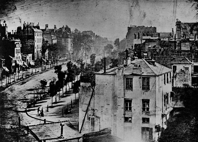 Bulwar du Temple w Paryżu, zdjęcie wykonane przez Louisa Daguerre'a w 1838 roku. W lewym dolnym rogu widać pucybuta i jego klienta. To jedynie ludzie na zdjęciu.