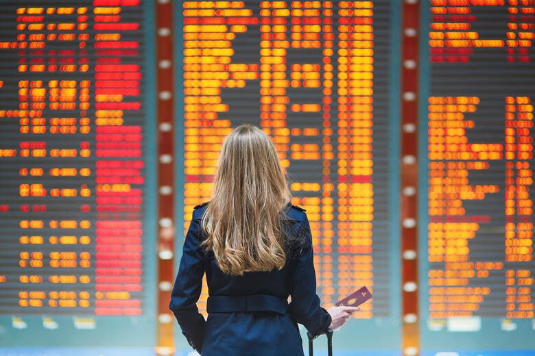 Kobieta na lotnisku sprawdza tablice odlotów