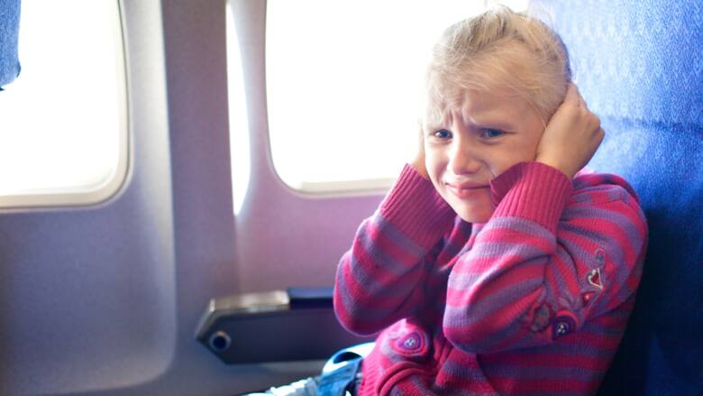 Dziecko siedzące w samolocie, cierpiące z powodu zatkanych uszu