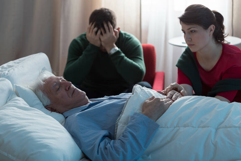 Ciężko chory pacjent i załamana rodzina przy łóżku