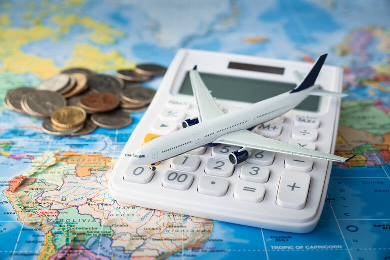 Kalkulator, pieniądze i model samolotu leżące na mapie świata
