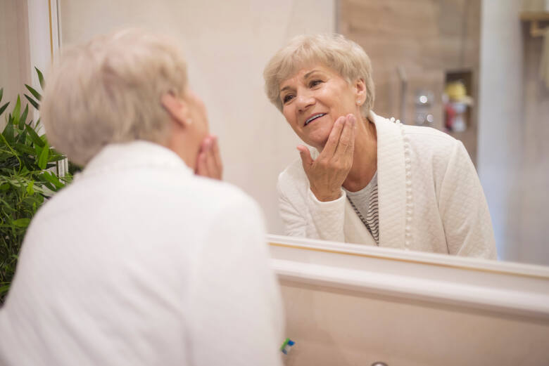 Starsza kobieta przegląda się w lustrze
