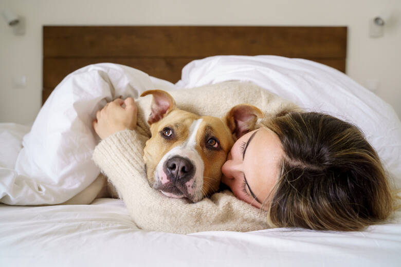 Młoda kobieta przytula w łóżku psa