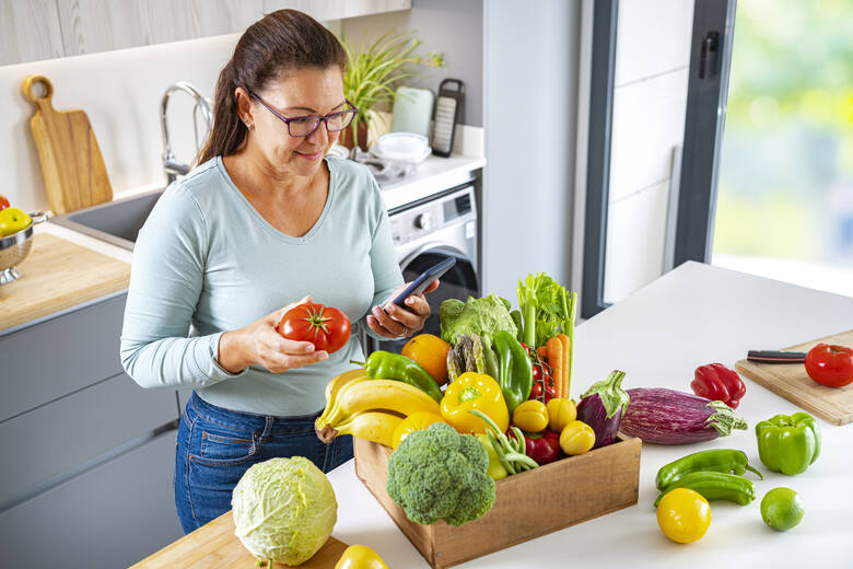 Kobieta w średnim wieku ze skrzynką pełną warzyw i owoców