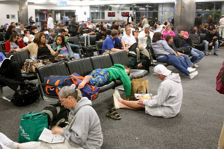 Zmęczeni pasażerowie odpoczywają na lotnisku