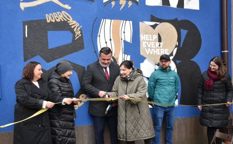 Moment uroczystego odsłonięcia muralu; wstęgę przecinają; przedstawiciele powiatu oświęcimskiego, artysta Łukasz Majerowski i przedstawicielki Muzeum