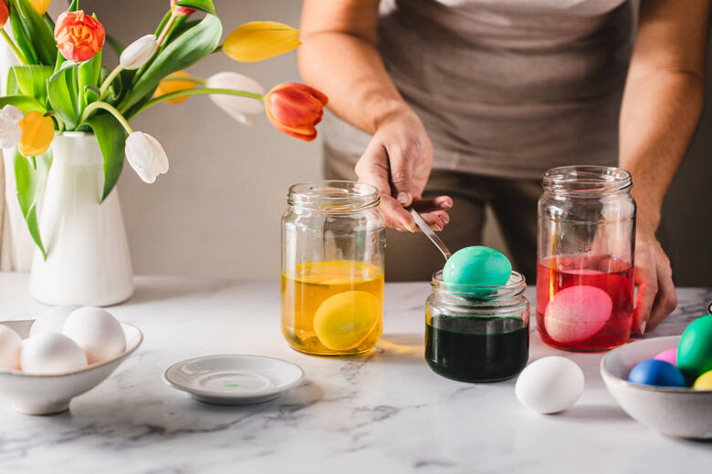 Kobieta maluje pisanki barwnikami do jajek