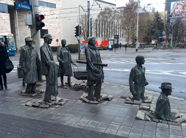 Grupa ludzkich rzeźb znajduje się u zbiegu ulic Świdnickiej i Piłsudskiego. Postaci przedstawione w instalacji trzymają przedmioty, charakterystyczne