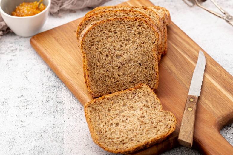 Widok od góry na pokrojone kromki chleba tostowego z mąki pełnoziarnistej na drewnianej desce