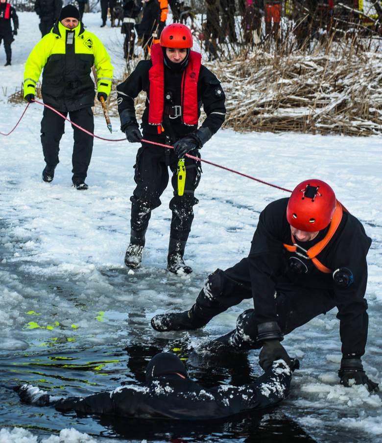 Ratownik podaje tonącemu wiosło (może być też kij, gałąź, koc) i pomaga mu wypełznąć na lód.