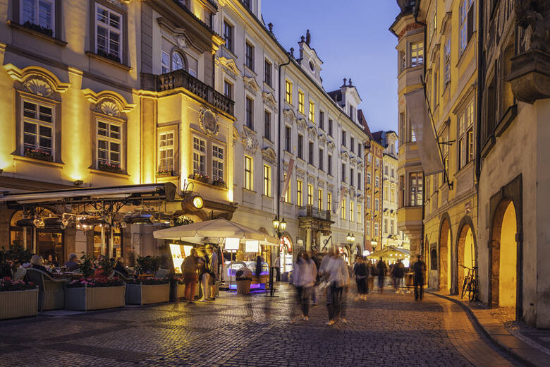 Turyści spacerujący ulicą Pragi o zmierzchu