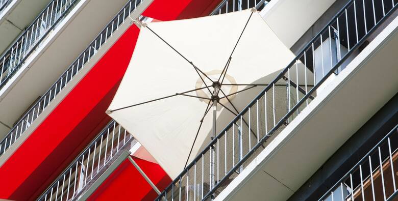 Nowoczesny parasol balkonowy w jasnym kolorze dodaje elegancji i funkcjonalności przestrzeni na balkonie, tworząc idealne miejsce do relaksu i chroniąc