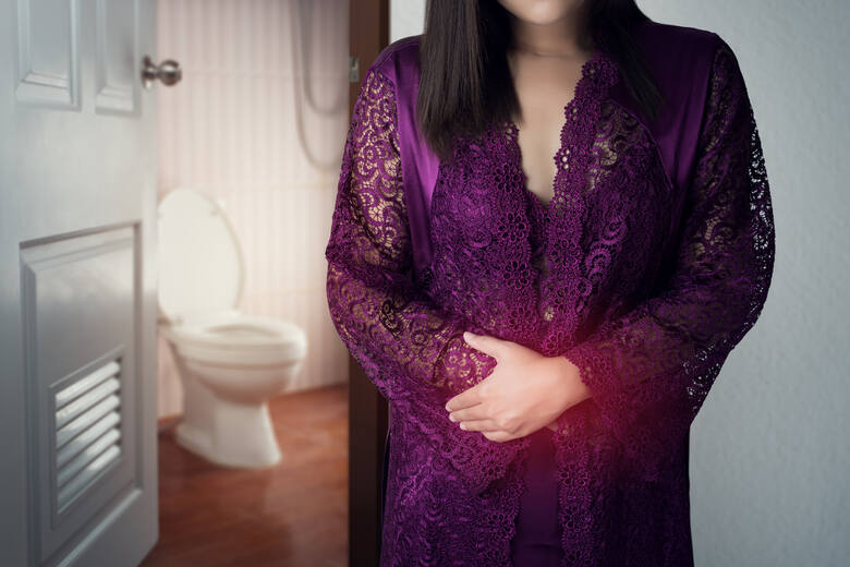 Kobieta w koszuli nocnej stoi w drzwiach toalety, w tle widać sedes