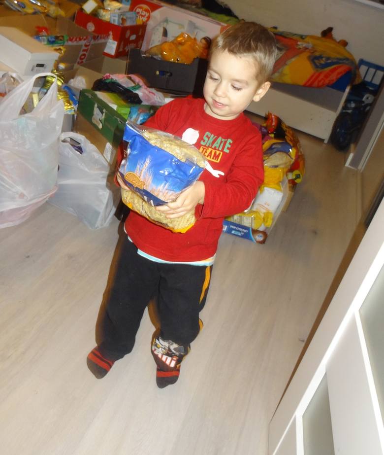 Trzyletni Aleksander pomaga pakować prezenty.