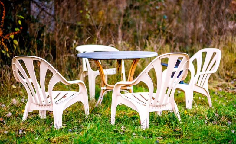białe plastikowe krzesła i stolik ustawione w ogrodzie