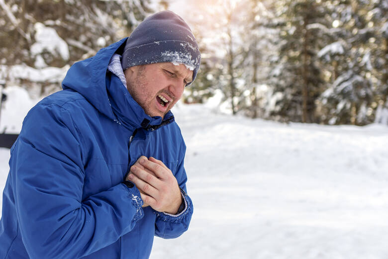Mężczyzna łapie się za serce w czasie spaceru w zimowy dzień