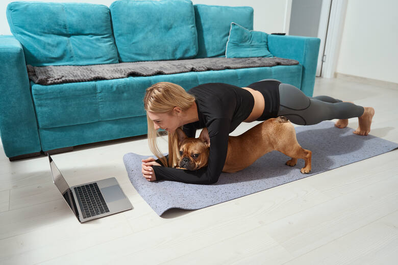 Młoda kobieta ćwiczy plank z psem na macie