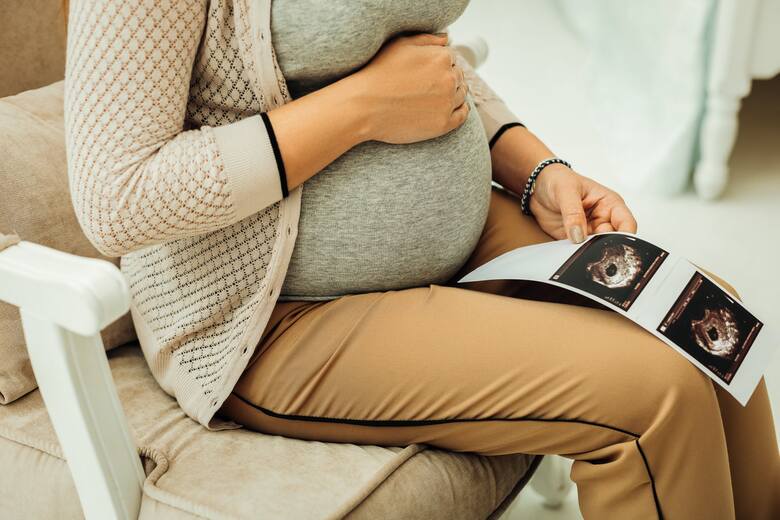 Kobieta w ciąży siedzi ze wynikami badania USG