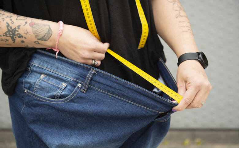 Młoda otyła kobieta mierzy się centymetrem