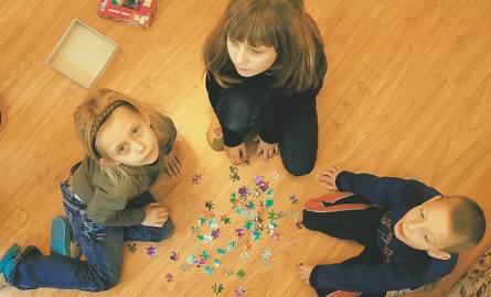 Aneta, Agata i Kuba rozkładają puzzle w nowym pokoju.