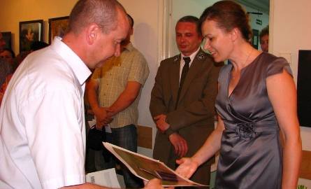Ireneusz Kaługa gratuluje Karolinie Barc ciekawej wystawy i wręcza prezent