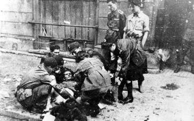 Podczas powstania warszawskiego kobiety angażowały się głównie w pracę łączniczek i sanitariuszek. Na zdjęciu: udzielanie pomocy rannemu na ulicy. Sierpień