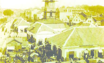 Rok 1897. Sklepy i sklepiki, kramy i kramiki, wielojęzyczny tłum. A z dachu Ratusza odpadają dachówki.