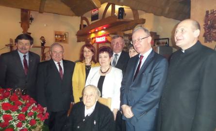Marian Kuś – wójt gminy Przyłęk (drugi z lewej)  i Wojciech Szmajda– przewodniczący Rady Gminy (piąty z lewej)  wręczyli jubilatce kosz ze 100 róż