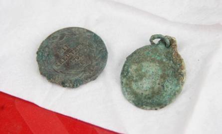 Austriacka moneta i medalik wydobyte z jednego z grobów.