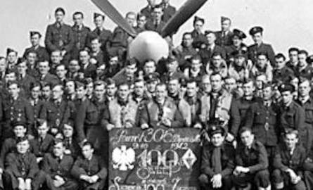 Pamiątkowa fotografia Dywizjonu Toruńskiego z okazji setnego lotu, co dokumentuje tablica, którą żołnierze trzymają przed sobą