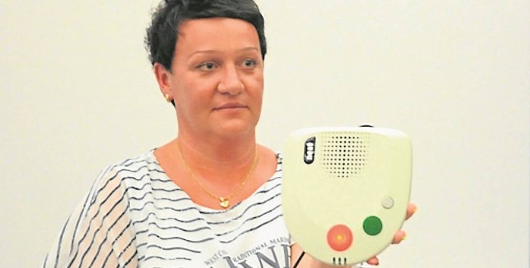 Agnieszka Świercz, kierownik Referatu Ekonomii Społecznej, pokazuje urządzenie, które będzie montowane u seniorów