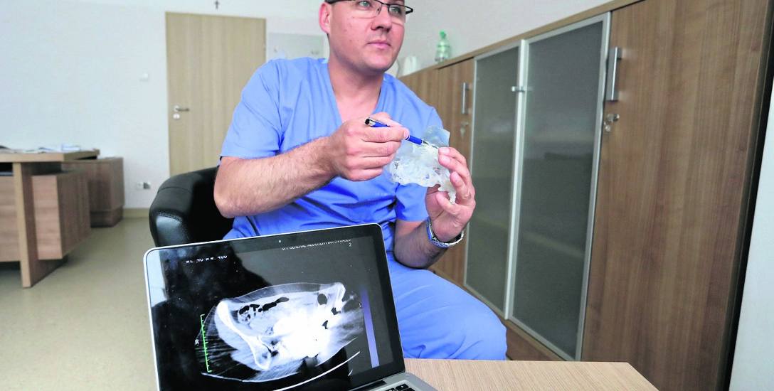 Dr hab. n. med Daniel Kotrych pokazuje model części miednicy z implantem. Na monitorze komputera widać zakłócenia przy prześwietleniu