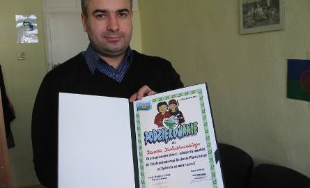 Karol Kwiatkowski pokazuje dyplom za przygotowanie radomskich dzieci romskich do międzynarodowego konkursu plastycznego "Spójrzcie na mnie