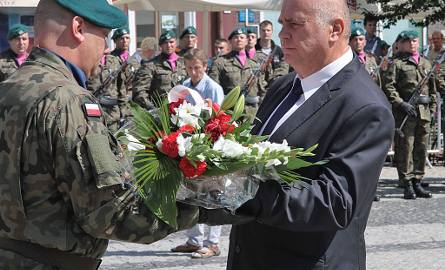 Poseł Janusz Dzięcioł przekazuje żołnierzowi kwiaty, do złożenia przed pomnikiem