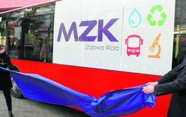 Prezes Miejskiego Zakładu Komunalnego Anna Pasztaleniec i prezydent Lucjusz Nadbereżny odsłaniają nowe logo MZK na szybie nowego autobusu.