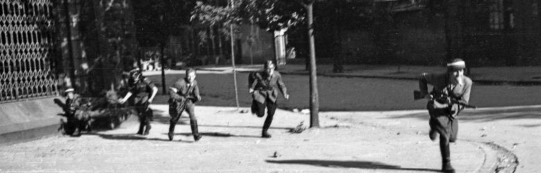 Powstańcy z kompanii „Koszta” przebiegający obok narożnika kamienicy wydawnictwa Gebethner i Wolff przy ul. Sienkiewicza 9. Sierpień 1944 r.
