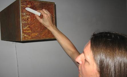 Alicja Duzel- Bilinska pisze kredą na słupie zamontowanym na ścianie galerii